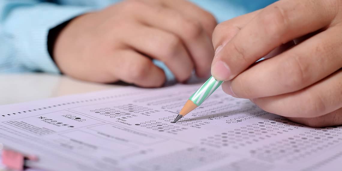 A person filling out a multiple choice test on an OMR sheet with a pencil