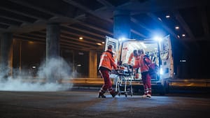 Team of EMS Paramedics React Quick to Bring Injured Patient to Healthcare Hospital and Get Him Out of Ambulance on a Stretcher. Emergency Care Assistants Help Young Man to Stay Alive After Accident.